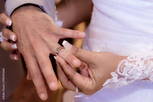 Close up hands of bride and groom putting on a wedding rings