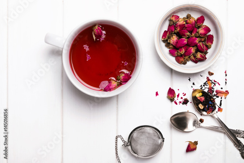 Herbal tea with roses on white wooden table