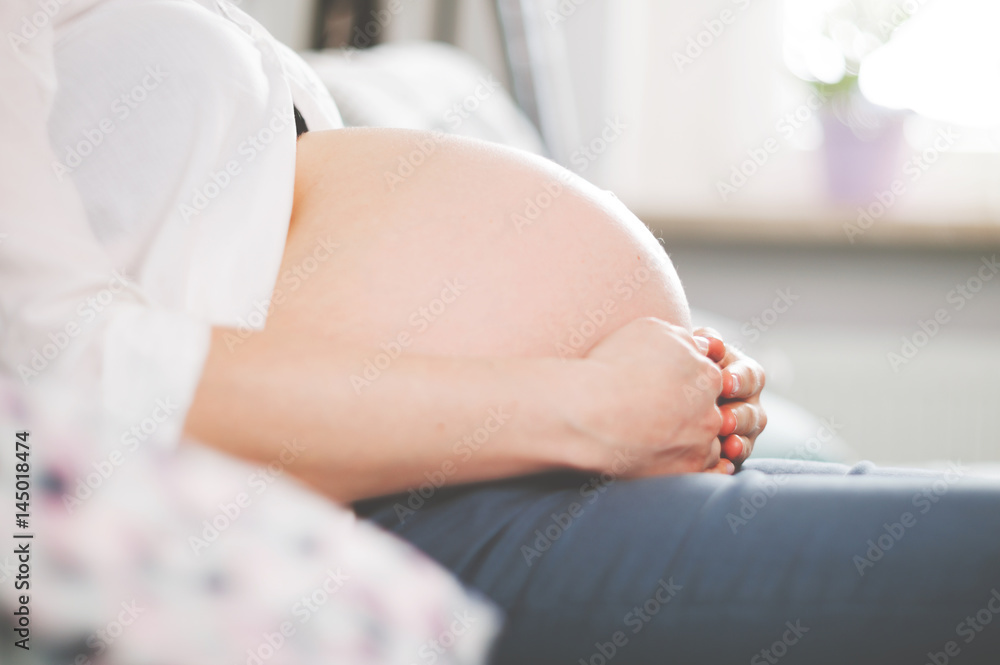 Φωτογραφία Belly of pregnant woman sitting on sofa at home