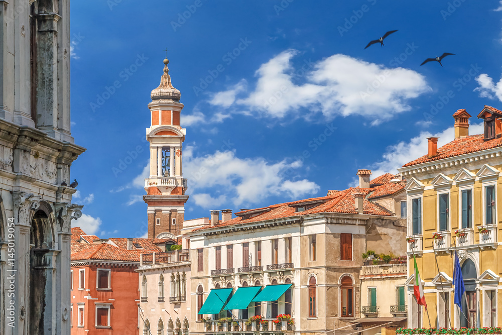 Beautiful sunny summer day view of Saints Apostles bell tower with old clock in Venice - Italy With colorful blue sky and white clouds