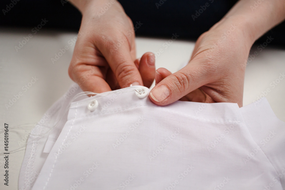 close-up picture of the hands of a seamstress at work with white fabric