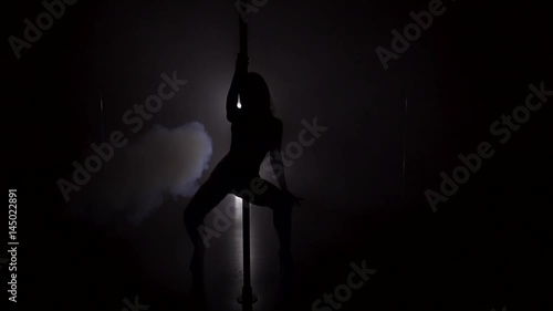 Silhouette of a slim woman dancing near the pole in strip shoes slow motion