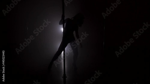 Silhouette of a woman dancing near the pole in strip shoes