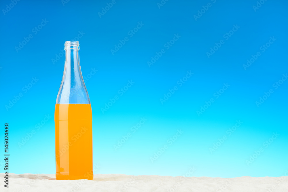 The bottle of orange juice on the beach The bottle of orange juice on the beach