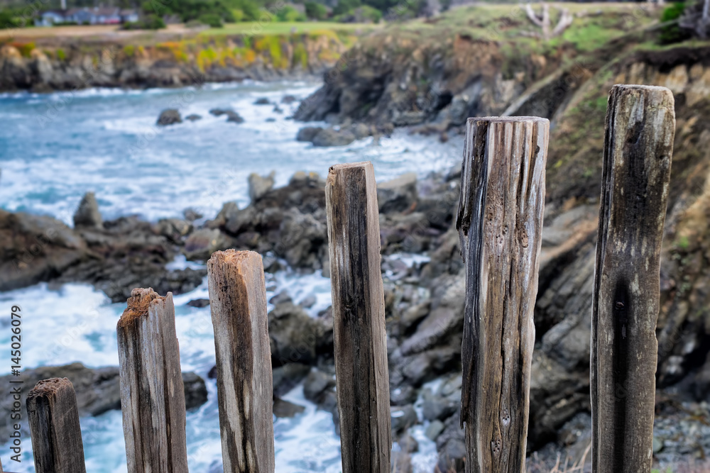 Pacific Ocean rocky Mendocino, California coast seascape viewed through picturesque old fence posts in the foreground Pacific Ocean rocky Mendocino, California coast seascape viewed through picturesque old fence posts in the foreground