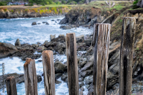 Pacific Ocean rocky Mendocino, California coast seascape viewed through picturesque old fence posts in the foreground