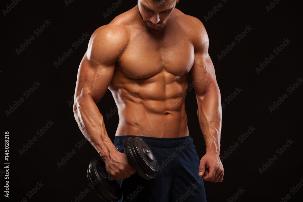 Handsome power athletic man with dumbbell is confidently looking forward. Strong bodybuilder with six pack, perfect abs, shoulders, biceps, triceps and chest Isolated on black background with Handsome power athletic man with dumbbell is confidently looking forward. Strong bodybuilder with six pack, perfect abs, shoulders, biceps, triceps and chest Isolated on black background with