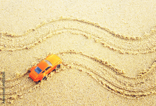Small children's orange machine on sea sand, top view. Conceptual image a travel by car, tourism, an adventure 