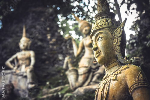 Asian sculptures symbolizing traditional culture and Buddhism in outdoors garden at sunset in Thailand