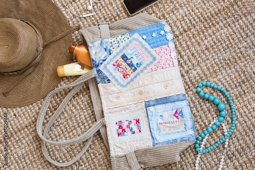 Set of summer items. Girl essentials with mobile phone and headphones, beads, hair brush, straw hat, sun cream for beach vacation on nature background. flat lay. top view. vacation concept. photo