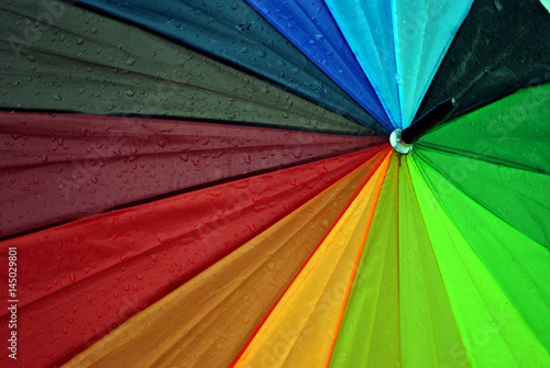 Close up of wet umbrella in rainbow colors; abstract background.