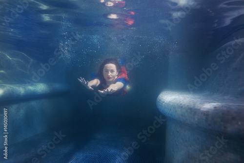 Woman swims under the water in the pool like a mermaid. © Petro