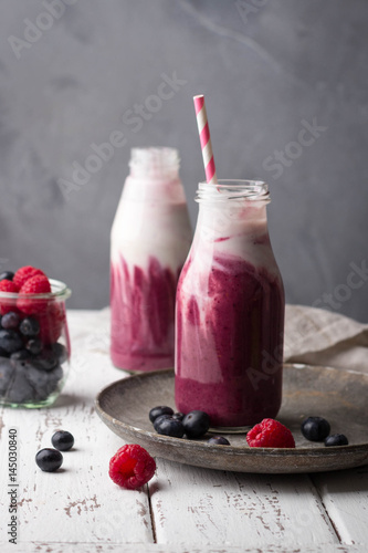 Fotografie Healthy berry smoothie with yogurt in bottle on light concrete background