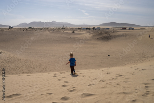 Little boy is walking in the sand dunes 