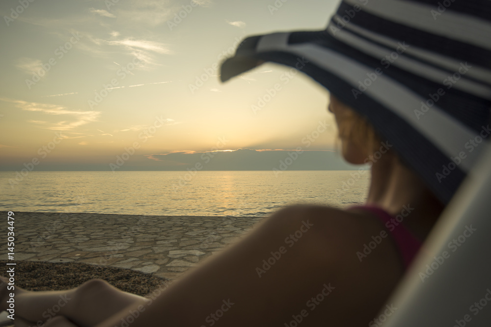 Fototapeta premium Woman with sunhat overlooking the ocean