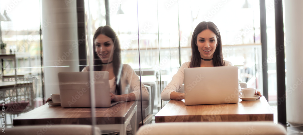 Smiling young woman drinking a coffee and surfing on internet Smiling young woman drinking a coffee and surfing on internet