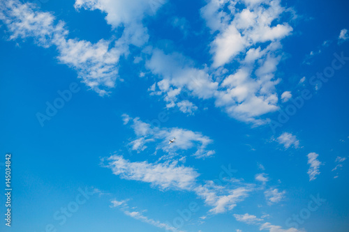 The plane flies in the blue sky. With white clouds.