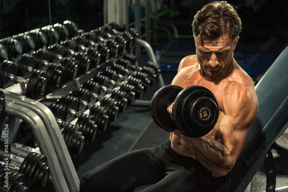 Mature shirtless bodybuilder man pumping iron at the gym Mature shirtless bodybuilder man pumping iron at the gym