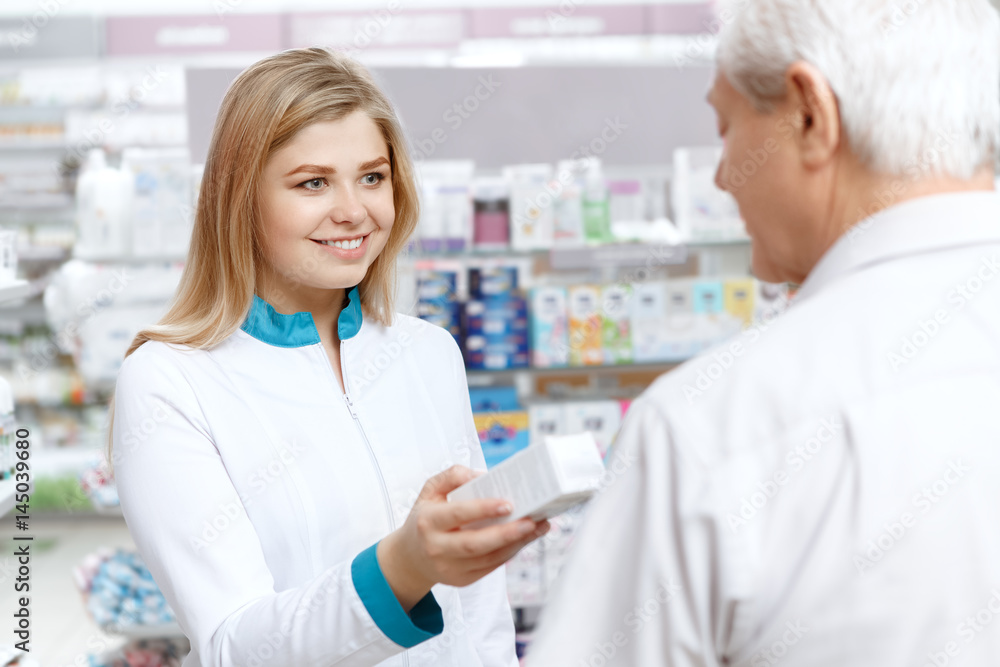 Young female pharmacist helping an elderly customer