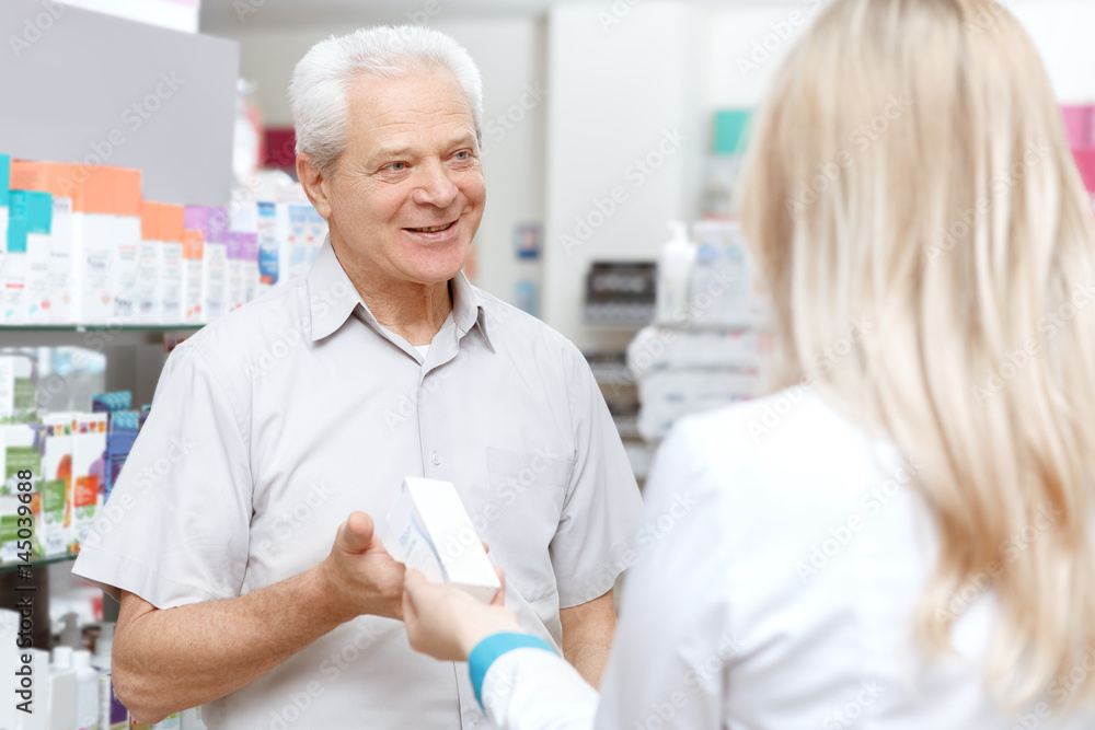 Obraz premium Young female pharmacist helping an elderly customer