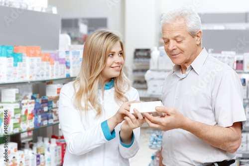 Young female pharmacist helping an elderly customer