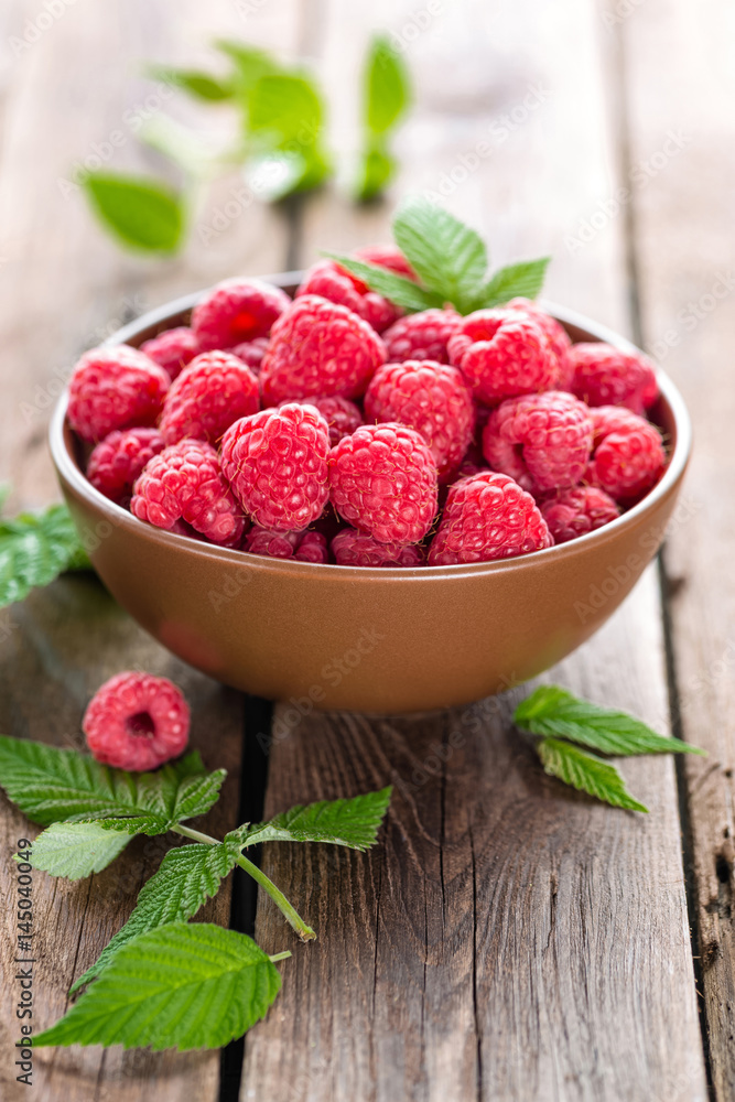 Fresh raspberry with leaves on wooden background Fresh raspberry with leaves on wooden background