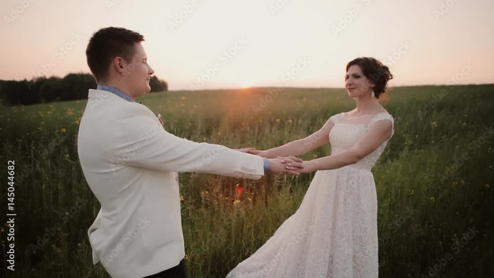 Beautiful couple in love look at each other and kiss in the nature on their wedding day in summertime. Wonderful sunset. Beautiful couple in love look at each other and kiss in the nature on their wedding day in summertime. Wonderful sunset.