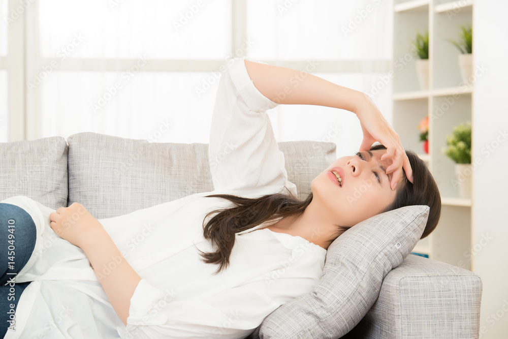 woman with headache lying on couch woman with headache lying on couch