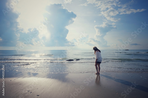 Happy woman relaxation on the sunny sea beach under sunlight sky with clouds at summer day, travel vacation, landscape beach background