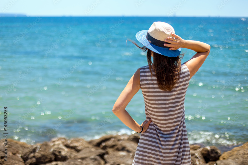 Travel woman on beach enjoying blue sea and sky