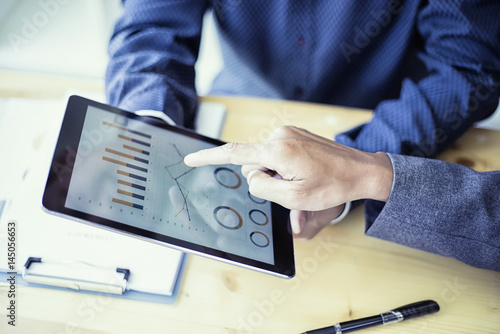 Business people analyzing investment charts on teblet in meeting room, Accounting concept