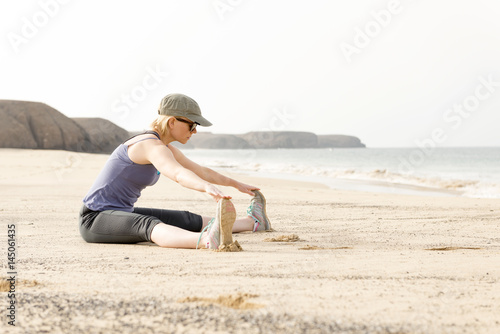 Woman in Sportswear Stretching Legs by the Sea Shore