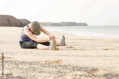 Lady Sitting on a Beach Doing Leg Stretches