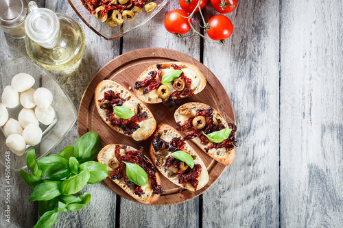 Appetizer bruschetta with sun-dried tomatoes, olives and mozarel