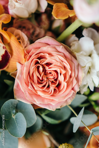 Colorful  bouquet of different fresh flowers against brick wall. Bunch of orchids, roses, freesia and eucalyptus leaves. Rustic flower background. Close up