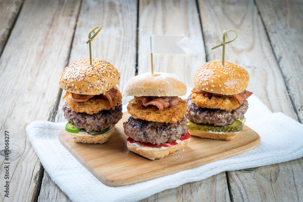Small beef sliders grilled burgers onion rings little buns bacon served as appetisers for sharing