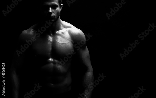 Cropped horizontal monochrome studio shot of a muscular athletic man posing shirtless copyspace fitness gym sports motivation energy power brutality concept.