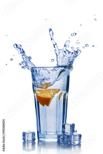 Splash in glass of blue water with orange slice and ice cube