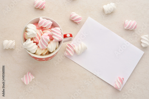 A blank sheet of paper, a glass of hot chocolate with marshmallows on a light background.