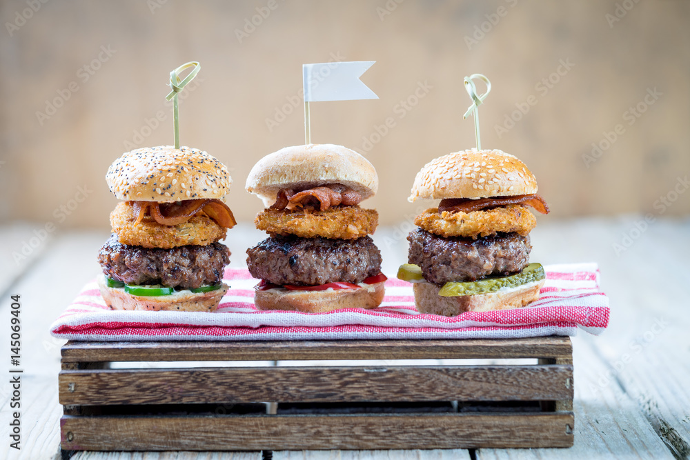 Small beef sliders grilled burgers onion rings little buns bacon served as appetisers for sharing