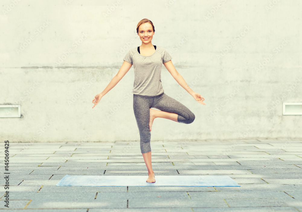 woman making yoga in tree pose on mat woman making yoga in tree pose on mat