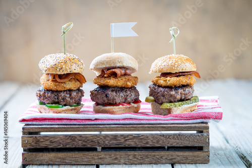 Obraz na płótnie Small beef sliders grilled burgers onion rings little buns bacon served as appetisers for sharing w salonie