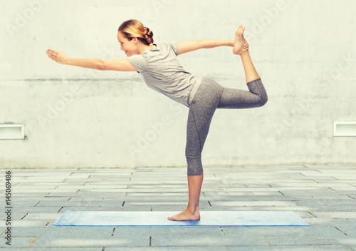 woman making yoga in lord of the dance pose on mat