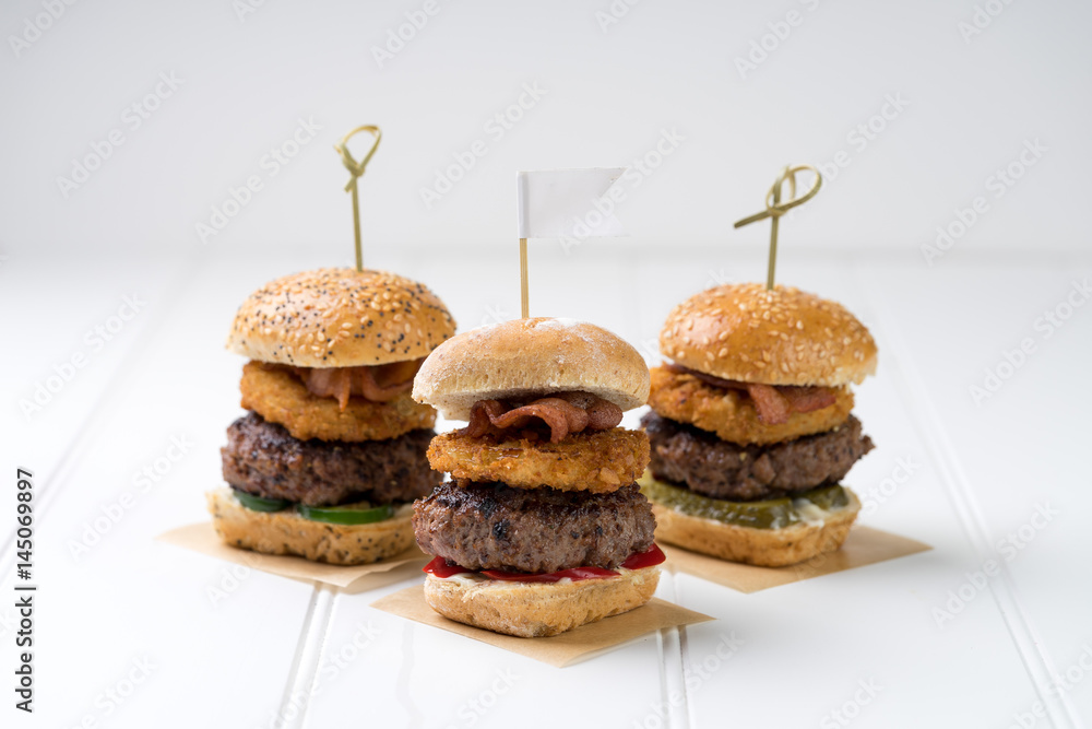 Small beef sliders grilled burgers onion rings little buns bacon served as appetisers for sharing