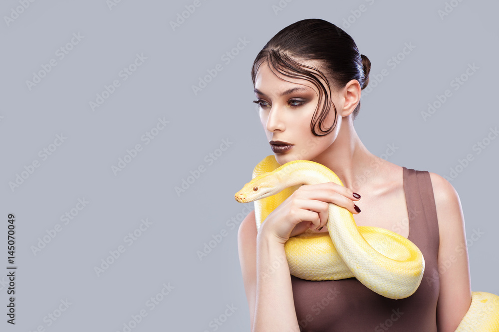 Beautiful brunette woman with a albine python. Fashion makeup, gray background Beautiful brunette woman with a albine python. Fashion makeup, gray background