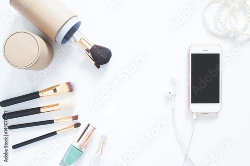 Flat lay of brushes with smartphone and pearl bracelet on white background with copy space