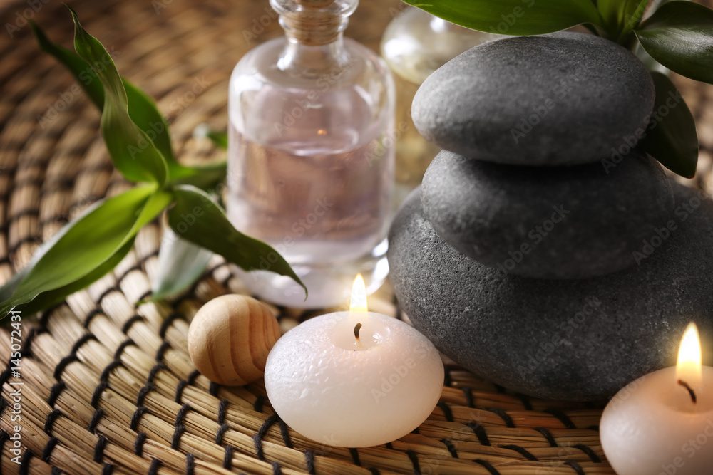 Spa stones with candles on wicker mat