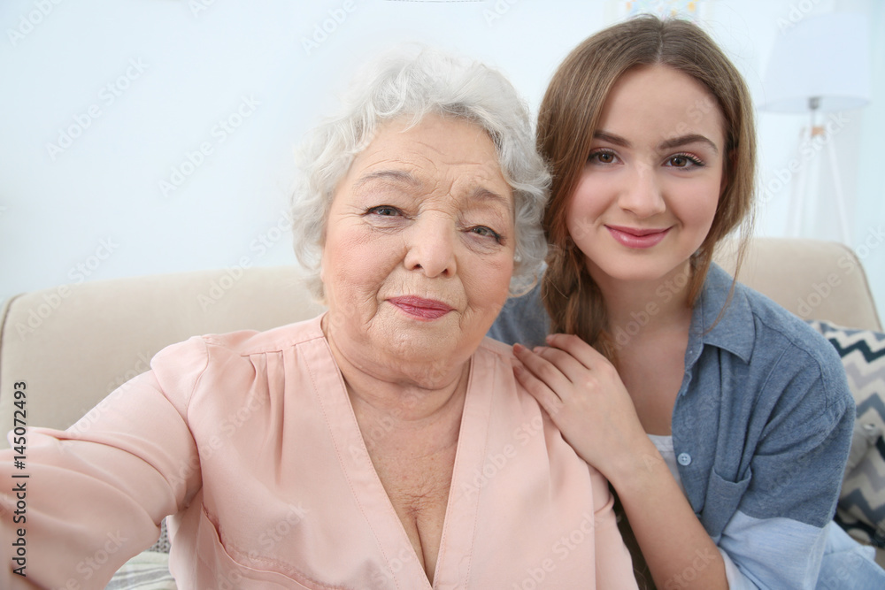 Beautiful girl with grandmother taking selfie on couch at home Beautiful girl with grandmother taking selfie on couch at home