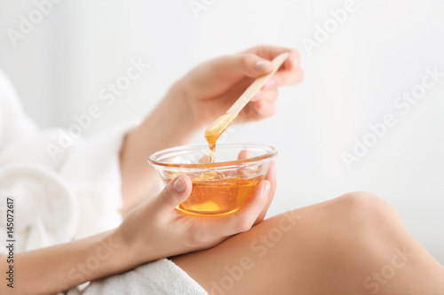 Woman holding bowl with hot wax on blurred background