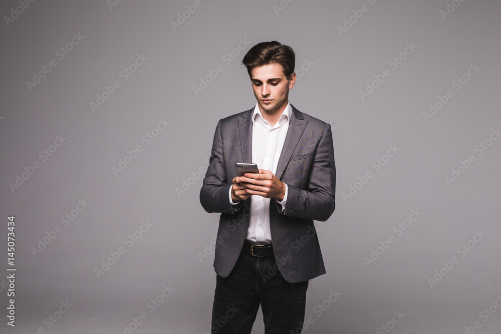 Portrait of Young business man texting a message with phone over gray background